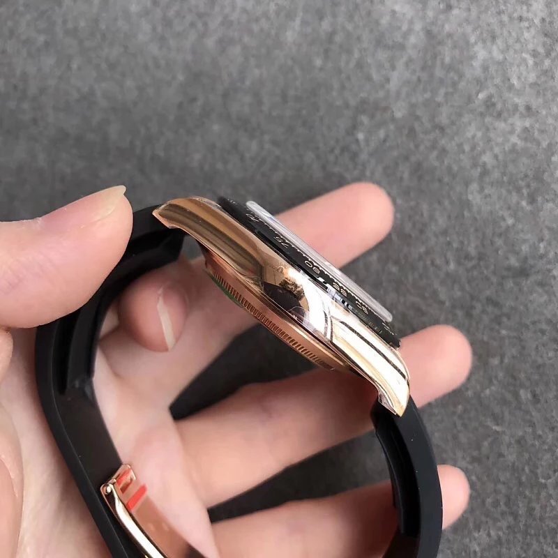 5 - Replica Rolex|Fake Rolex|the best rolex watch factory Side view of a rose-gold wristwatch with a black strap being held between fingers